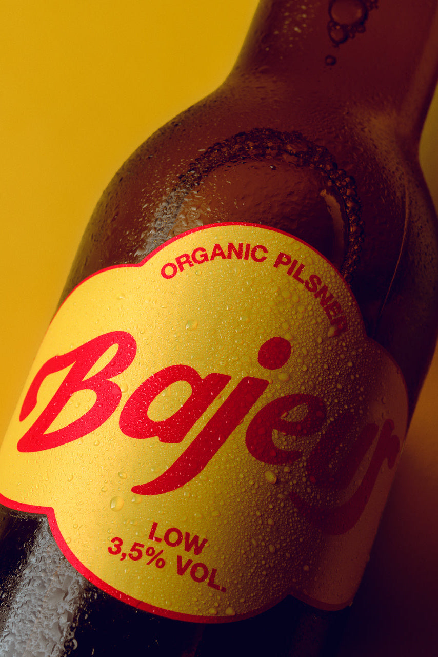 Bottle of Bajeur Organic Pilsner with a yellow label on a yellow background