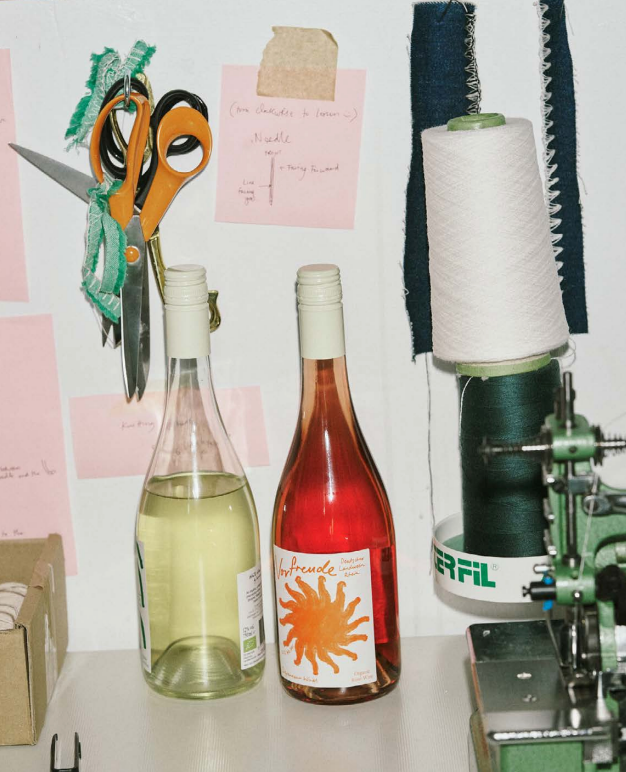 Two organic Depanneur wine bottles on a table with sewing equipment and supplies in the background.