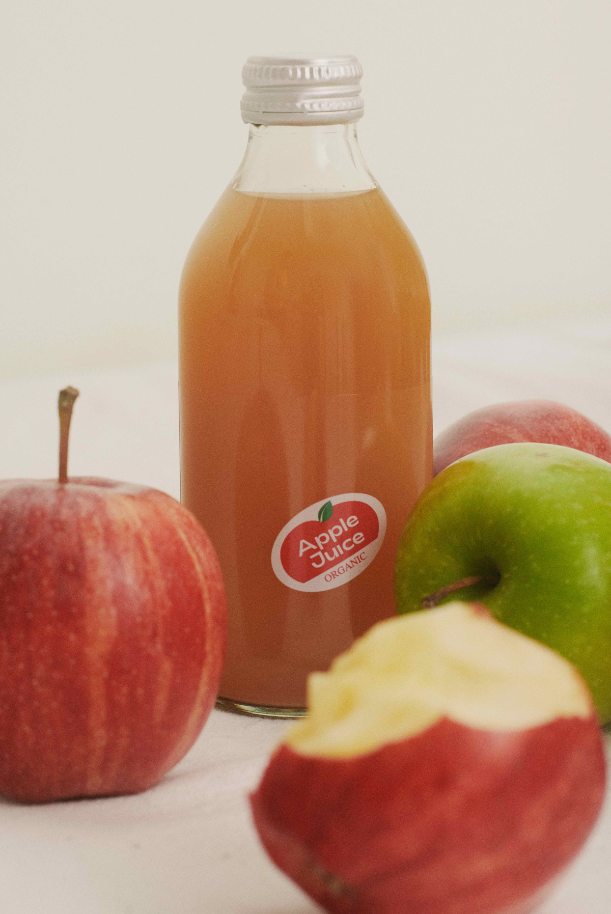 A bottle of Depanneur organic apple juice with apples around it. 