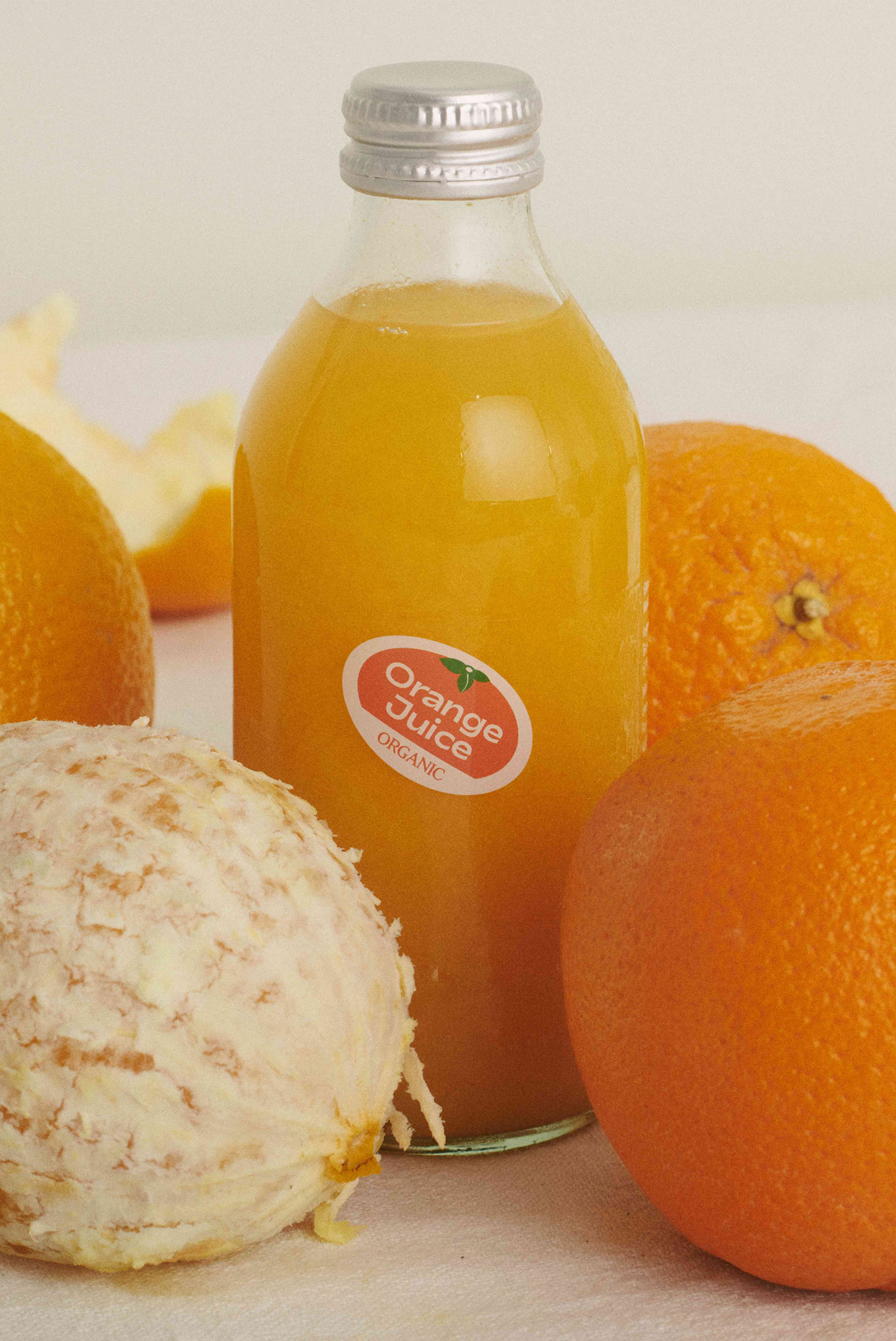 A bottle of organic orange juice with oranges next to it 
